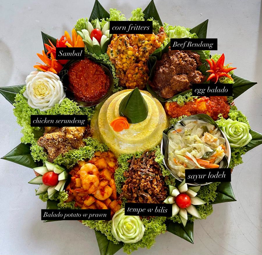 Tumpeng with yellow rice, labelled: beef rendang, chicken serundeng, egg balado, balado potato with prawn, sayur lodeh, tempe with bilis, corn fritters, sambal